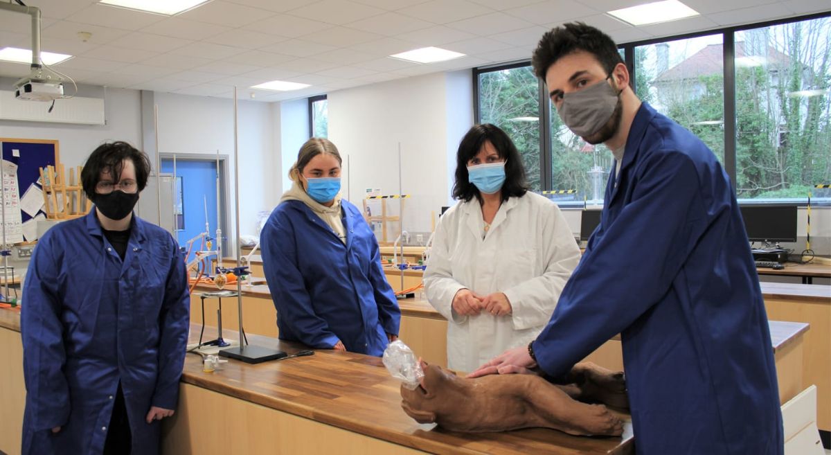 Three Animal Care Students in blue lab coats with CasPer CPR training resource learning CPR with Lecturer in white lab coat.